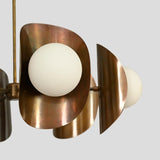 Close-up view of solid brass chandelier with curved bowl shade and white globe bulb, handcrafted modern ceiling light.
