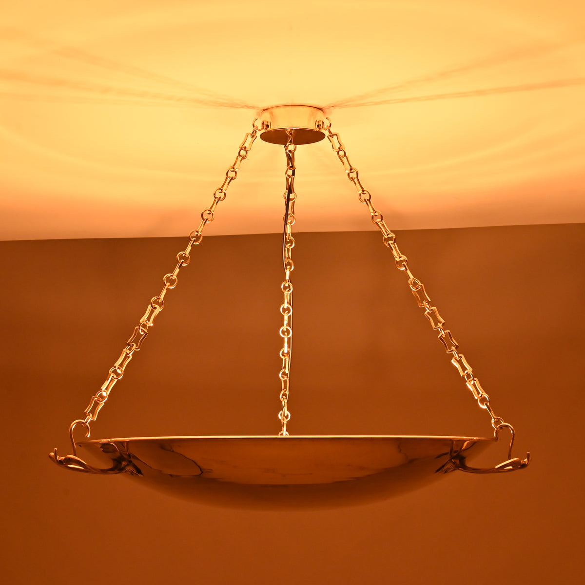 Full view of lit brass bowl chandelier spreading ambient light in classic interiors