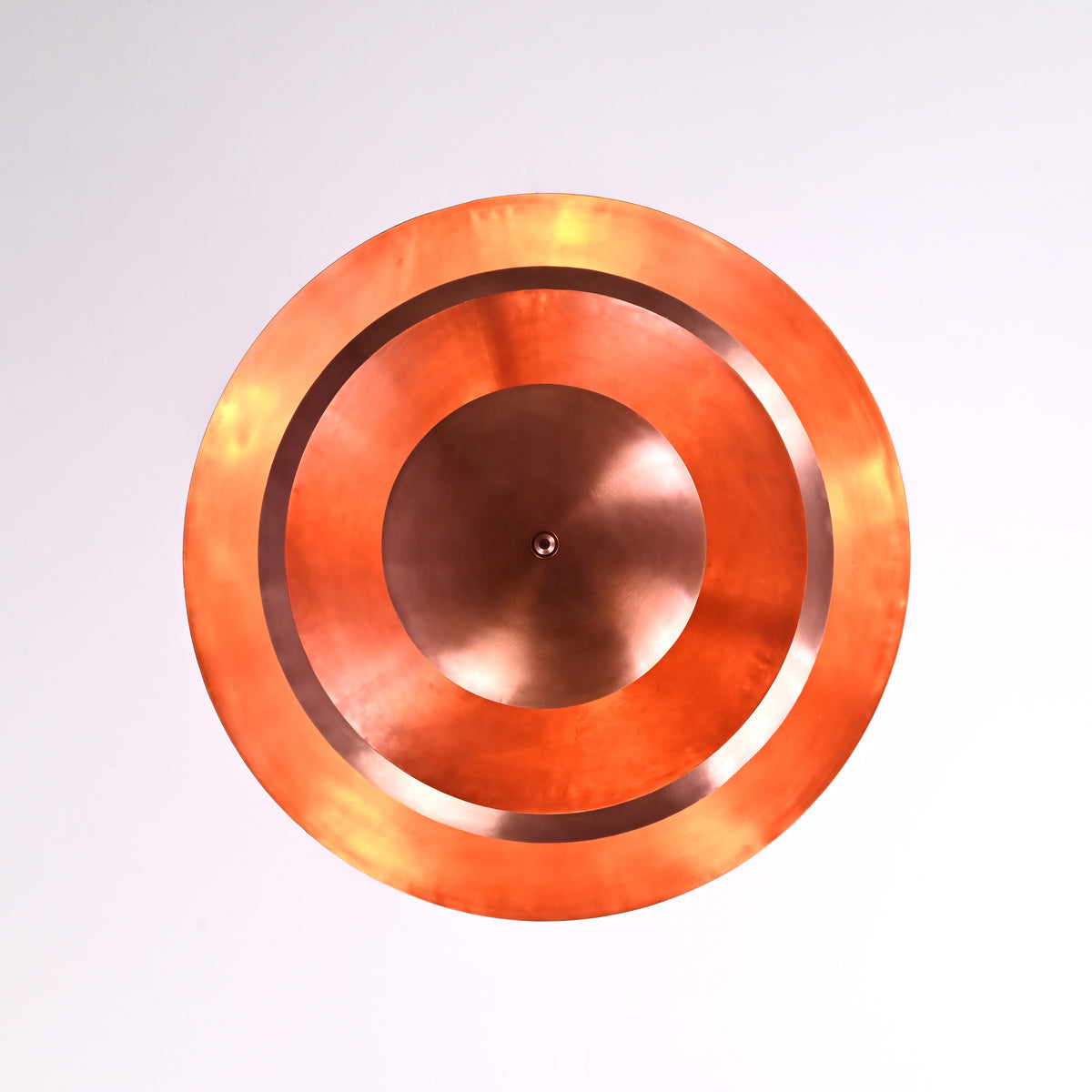 Warm glowing bottom view of the multi-layer brass chandelier with soft indirect lighting illuminating the circular copper shades.