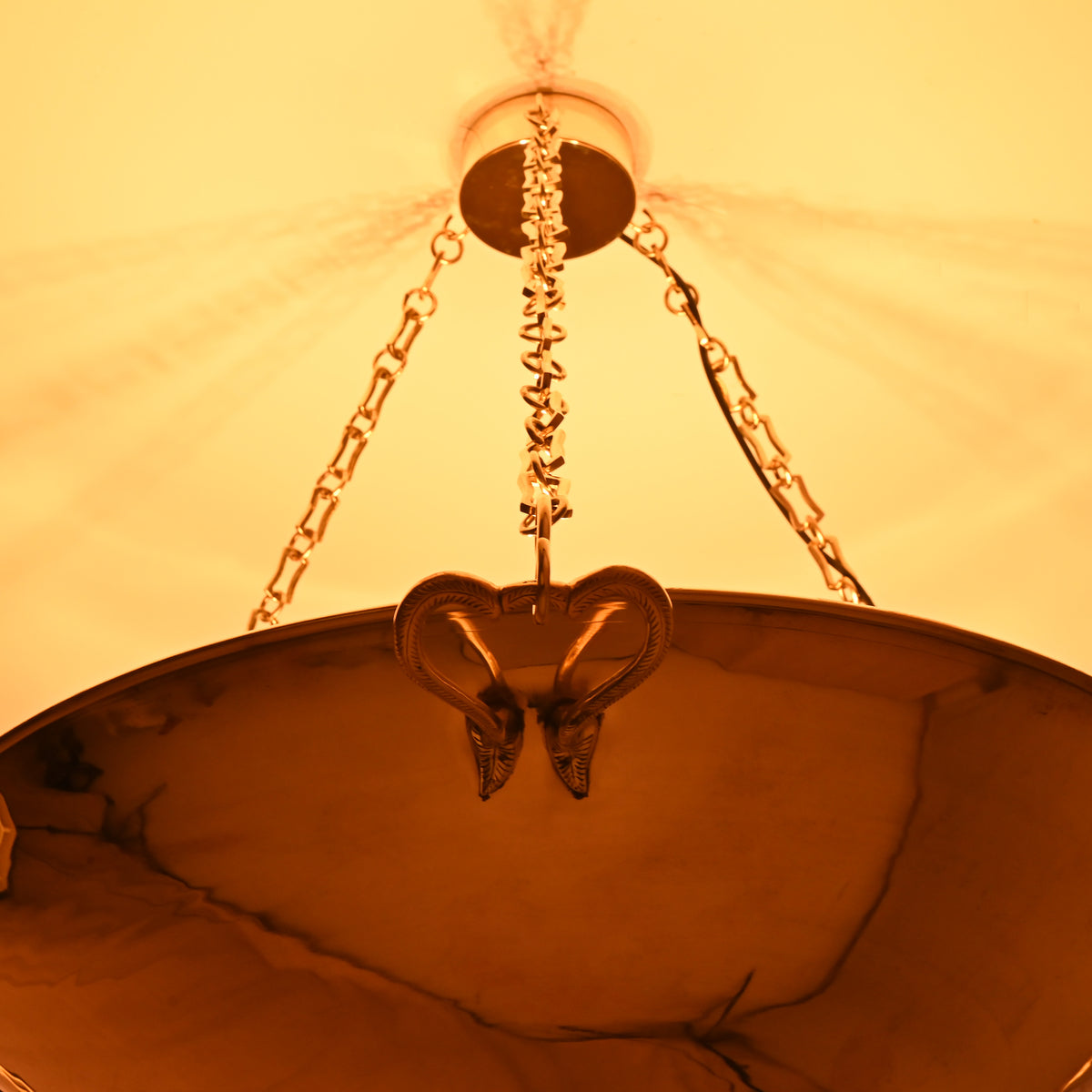 Detailed view of heart-shaped ram brass handle on chandelier with golden links