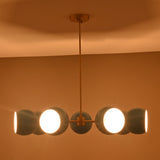Modern chandelier with three illuminated lights against a warm-toned wall.