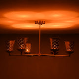 Perforated brass cone shades producing soft glowing light in a modern handcrafted chandelier by Brass Leaf Studio.