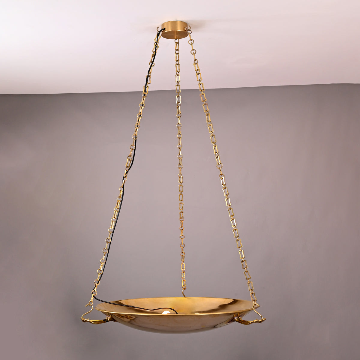 Side angle view of brass bowl chandelier suspended with four chain links and decorative handles
