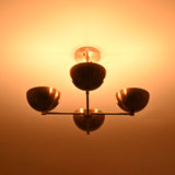 Golden brass chandelier with four bowl shades glowing warmly and casting ambient ceiling light