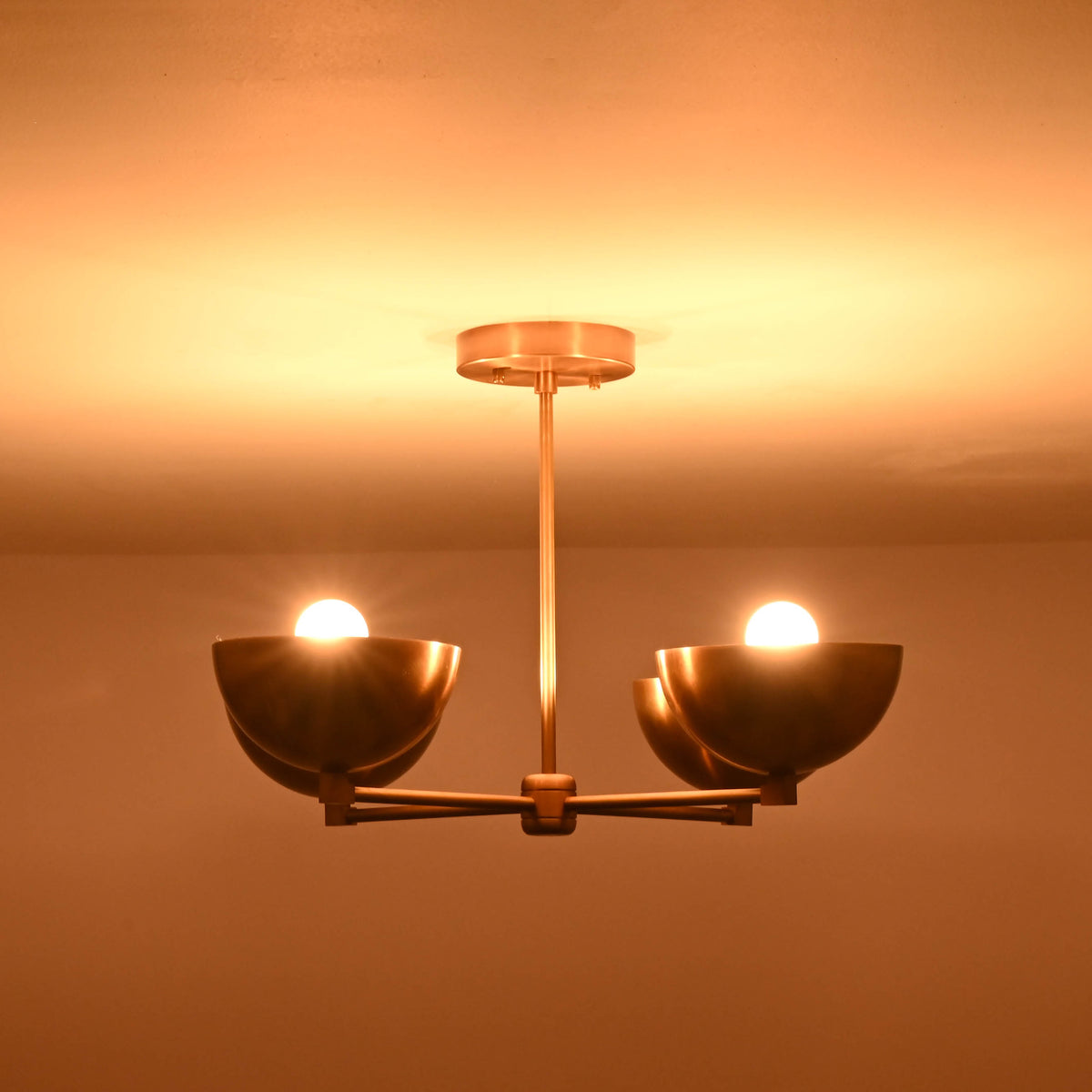 Golden brass chandelier with upward lighting effect illuminating a modern interior ceiling