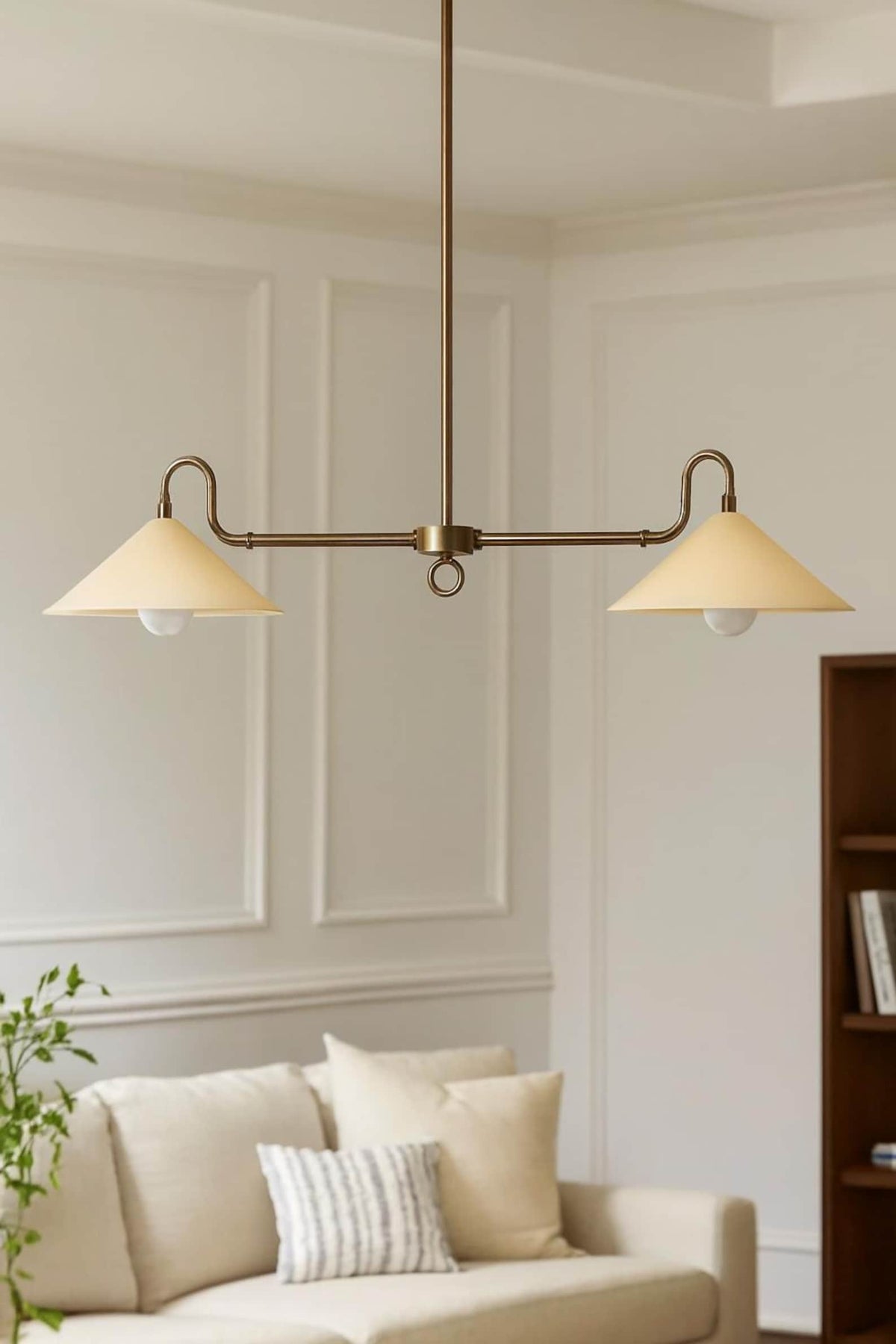 Mid-century modern brass cone chandelier suspended above a sofa with clean lines and balanced symmetry