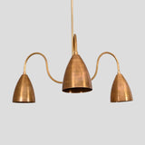 Close-up view of brass chandelier with three cone-shaped shades and sculptural arms, modern handmade ceiling light.