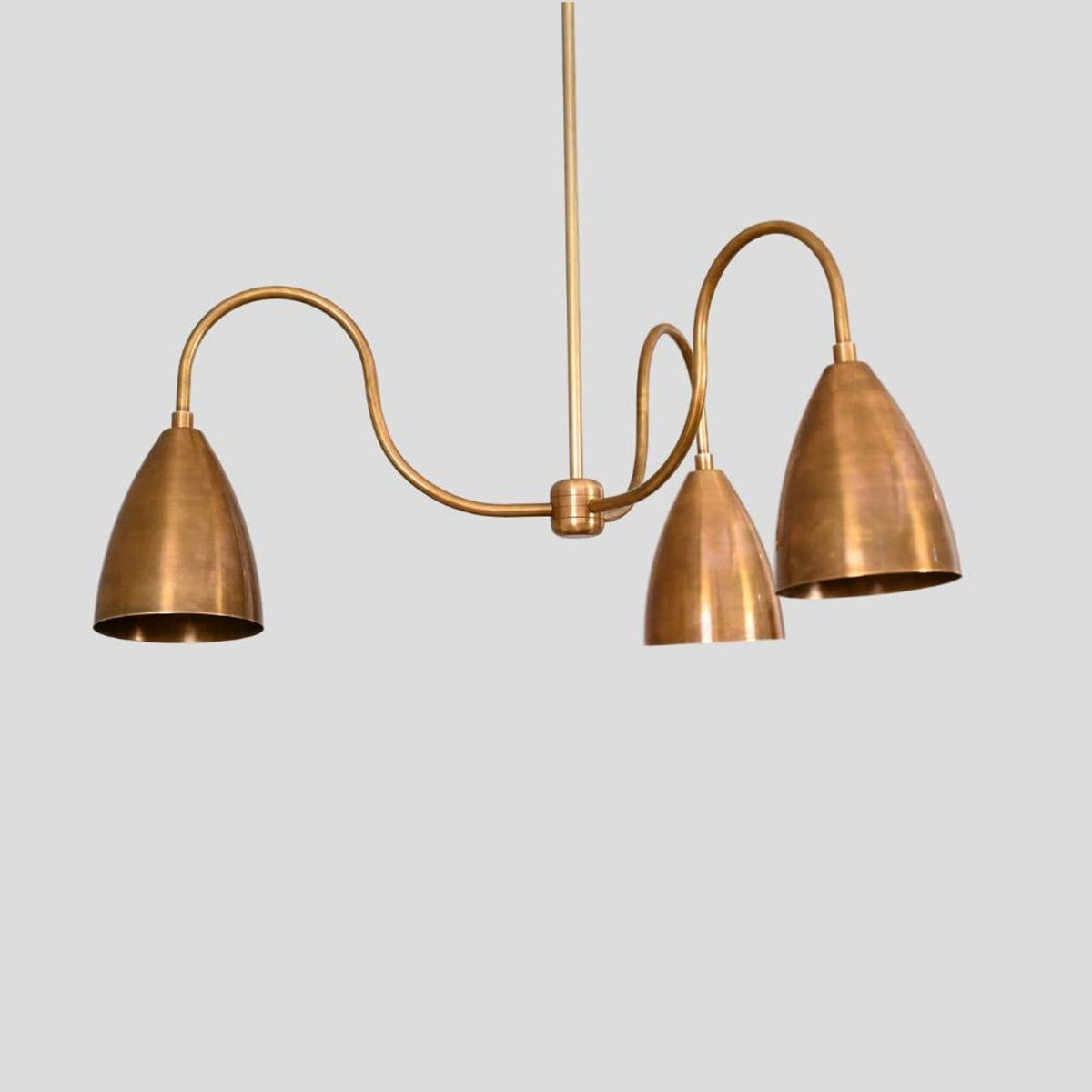 Detailed angled view of brass chandelier with three cone-shaped shades, handcrafted in premium solid brass for modern interiors.
