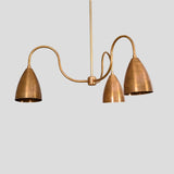 Detailed angled view of brass chandelier with three cone-shaped shades, handcrafted in premium solid brass for modern interiors.