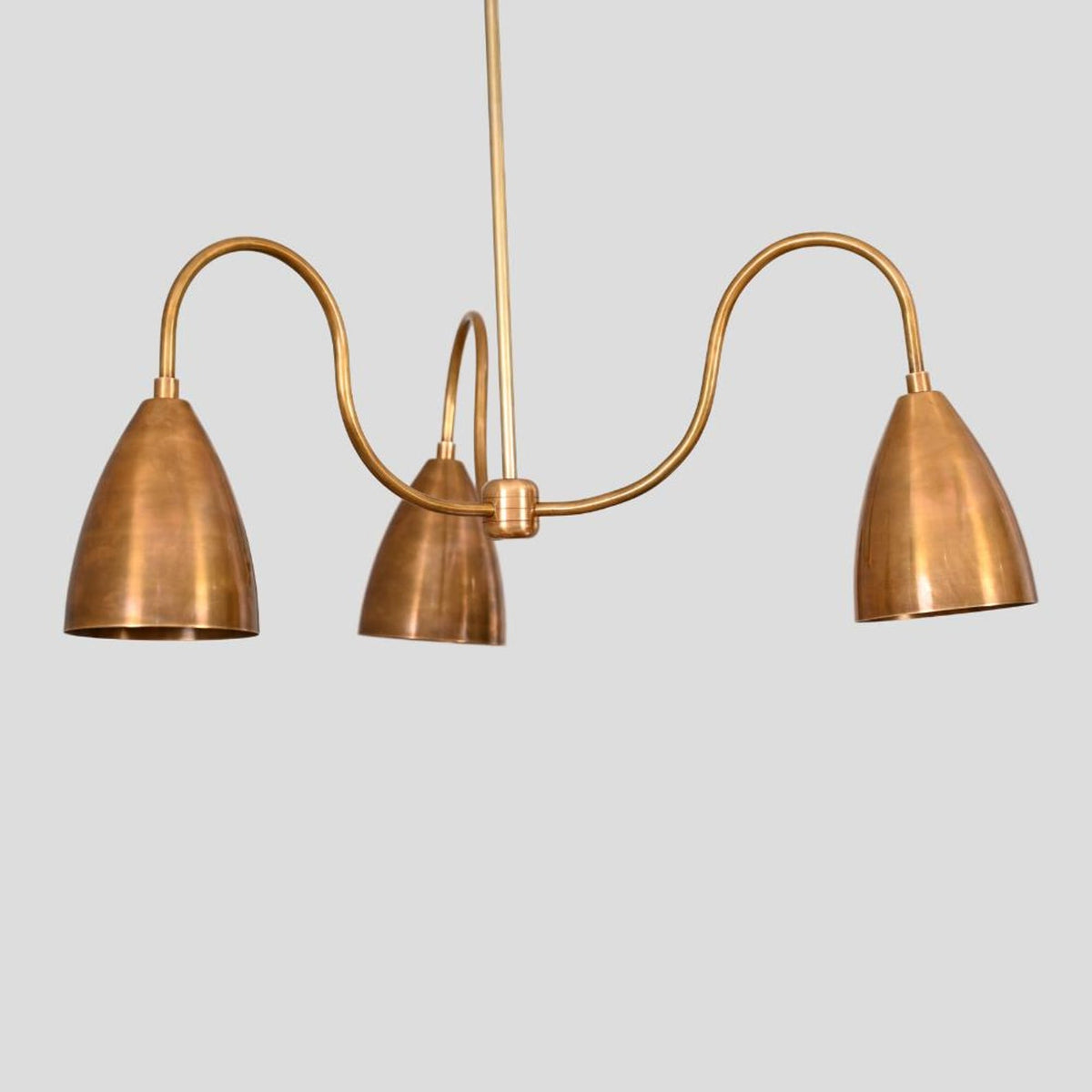 Diagonal perspective of handmade brass chandelier showing cone shades and curved arms with elegant lacquer-coated finish.
