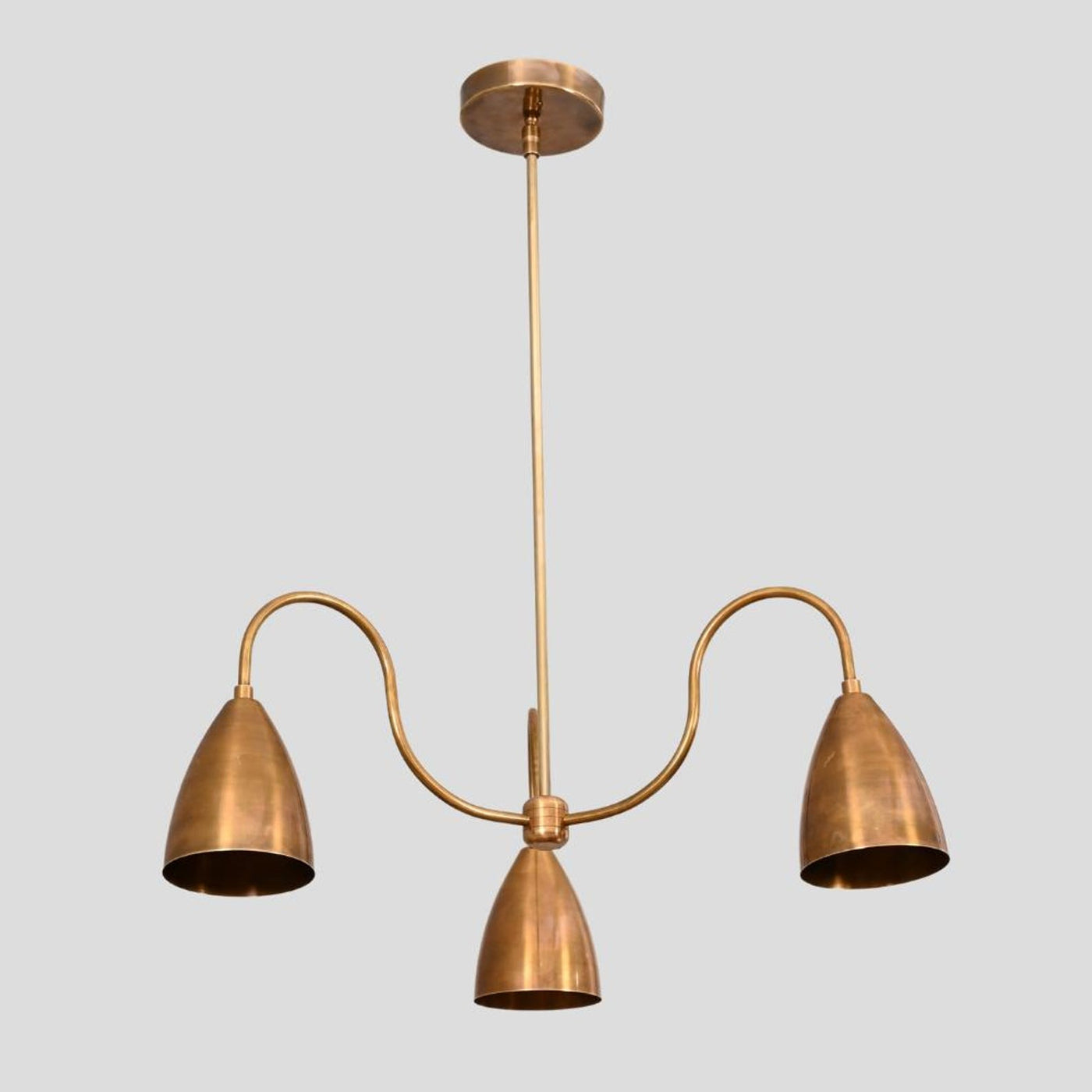 Handmade brass 3-light chandelier with cone-shaped shades and curved arms, minimalist industrial ceiling light by Brass Leaf Studio.