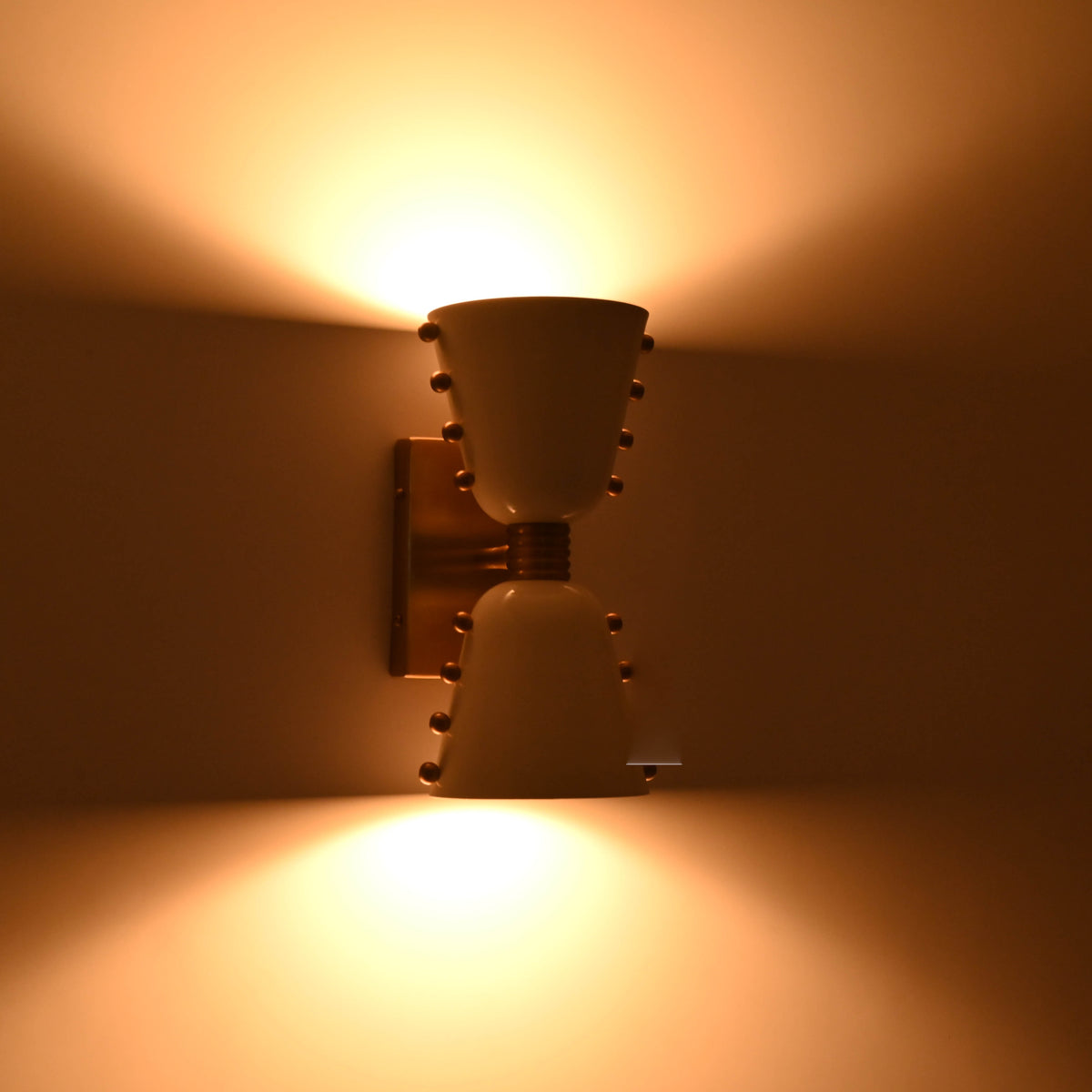 Solid brass cone shade wall sconce shown from side angle with rectangular backplate and brass arm
