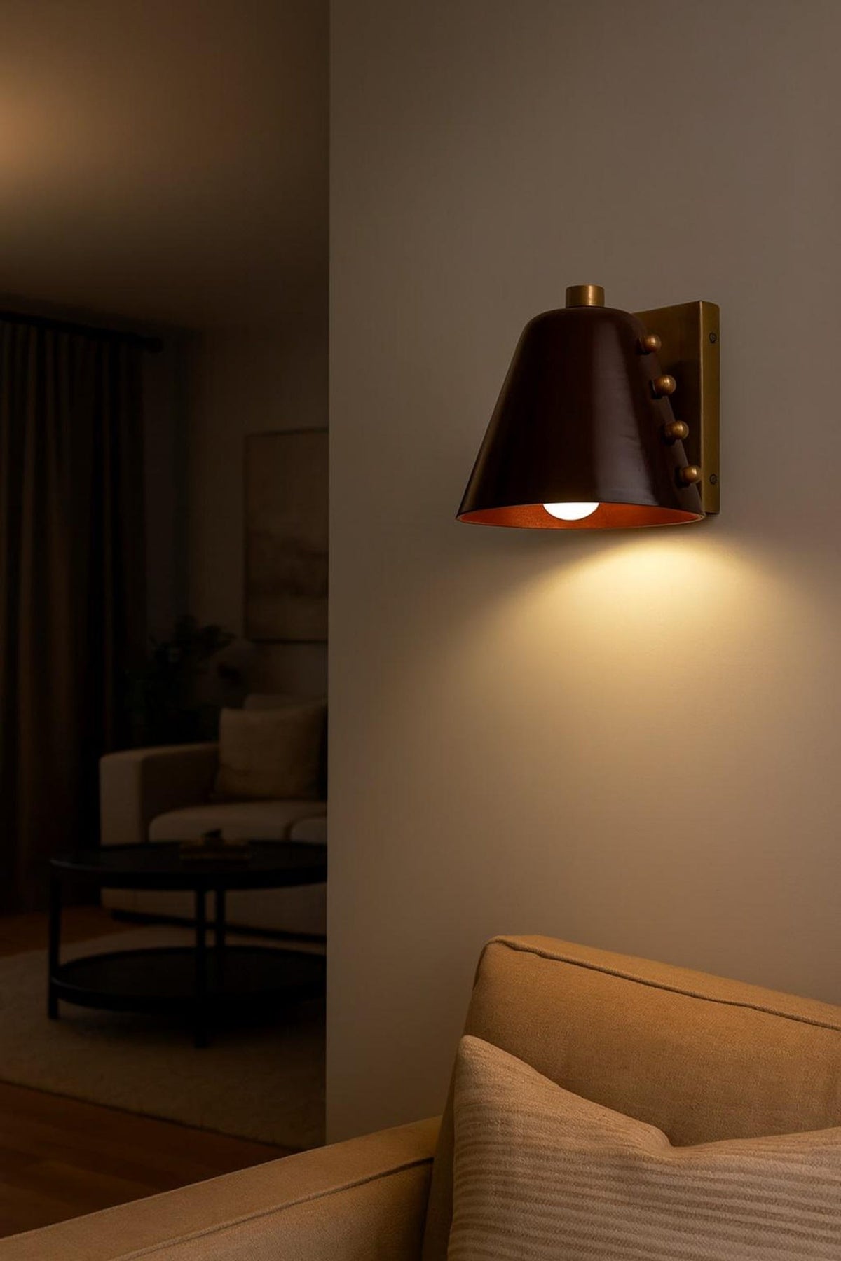 Brass cone wall light installed on wall providing warm ambient lighting in living room
