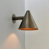 Handmade brass cone wall sconce with minimalist conical shade casting downward light
