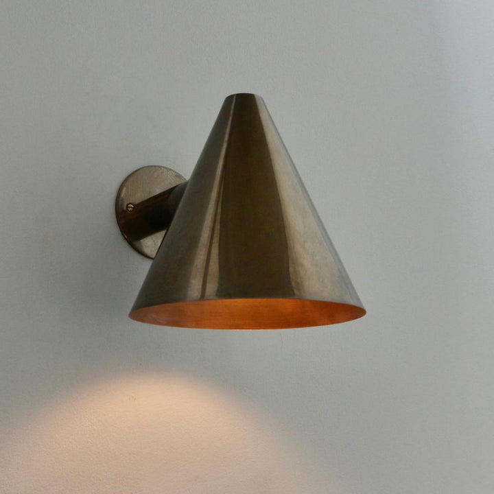 Solid brass wall light with cone-shaped shade mounted on round brass base