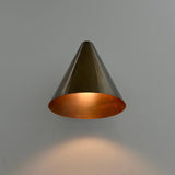 Brass cone wall sconce with wide conical shade creating warm focused illumination