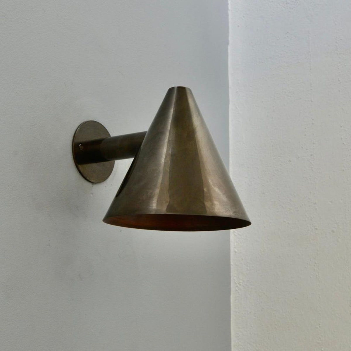 Angled view of brass cone wall sconce featuring handcrafted conical shade design