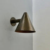 Angled view of brass cone wall sconce featuring handcrafted conical shade design