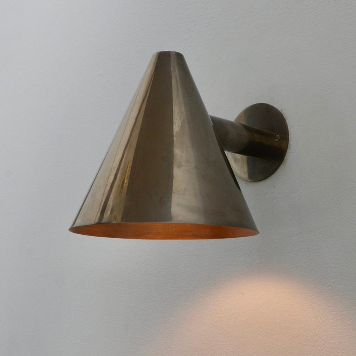 Handmade brass wall light with minimalist cone shade for contemporary interiors