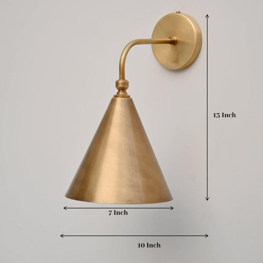 Handmade brass cone wall sconce illuminated on wall, modern minimalist lighting by Brass Leaf Studio