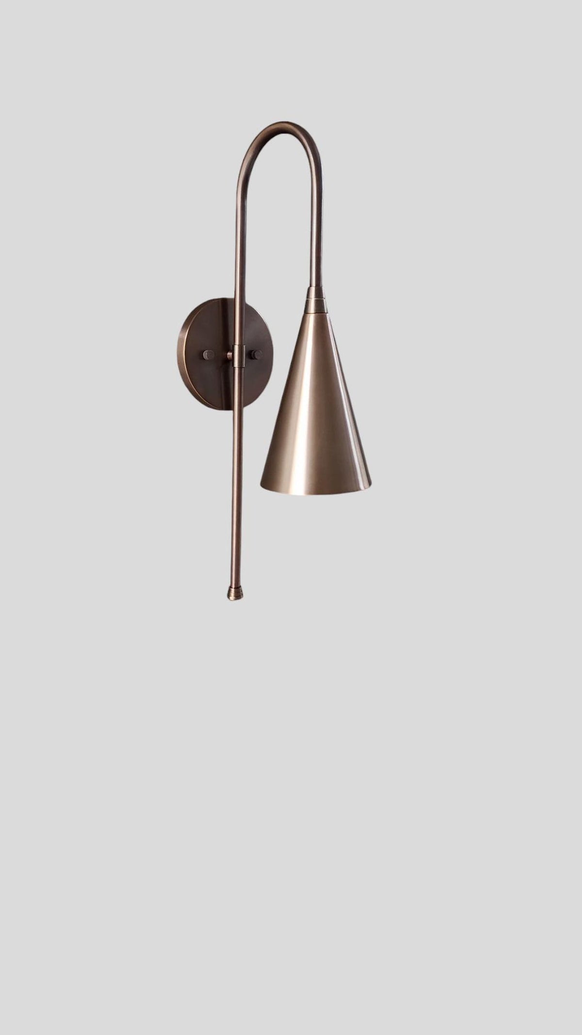 Minimal front view of brass cone wall sconce with elegant curved brass arm