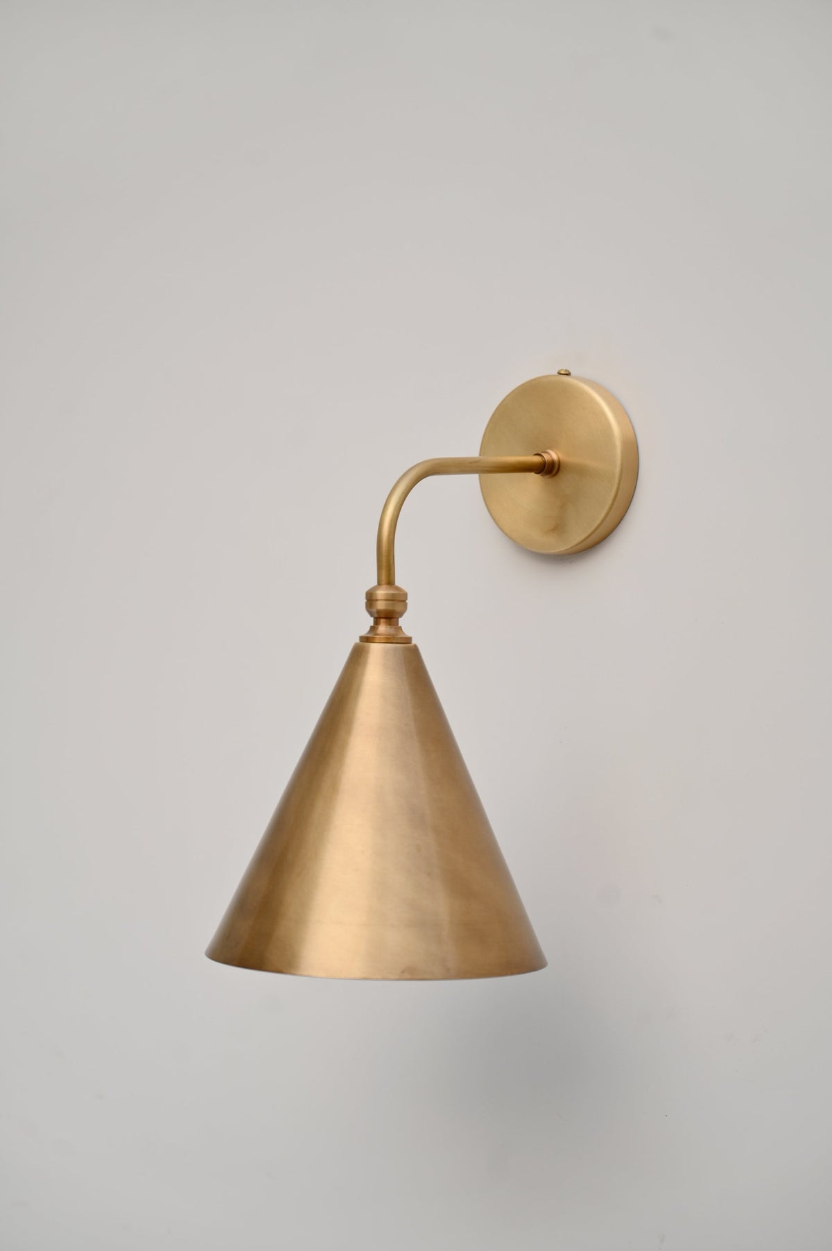 Minimalist brass cone wall sconce with industrial design, perfect for bedrooms, cafes, and boutique interiors
