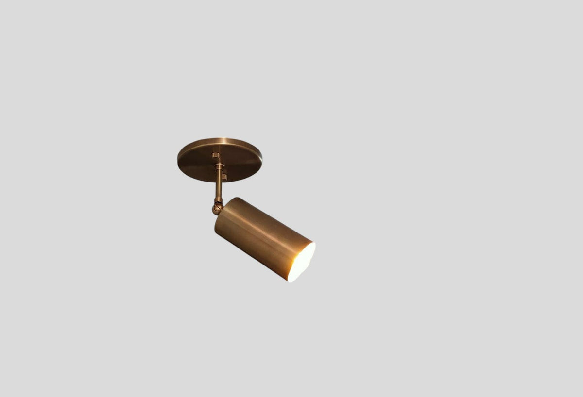Brushed brass ceiling spotlight illuminated with warm light, adjustable cylinder design by Brass Leaf Studio
