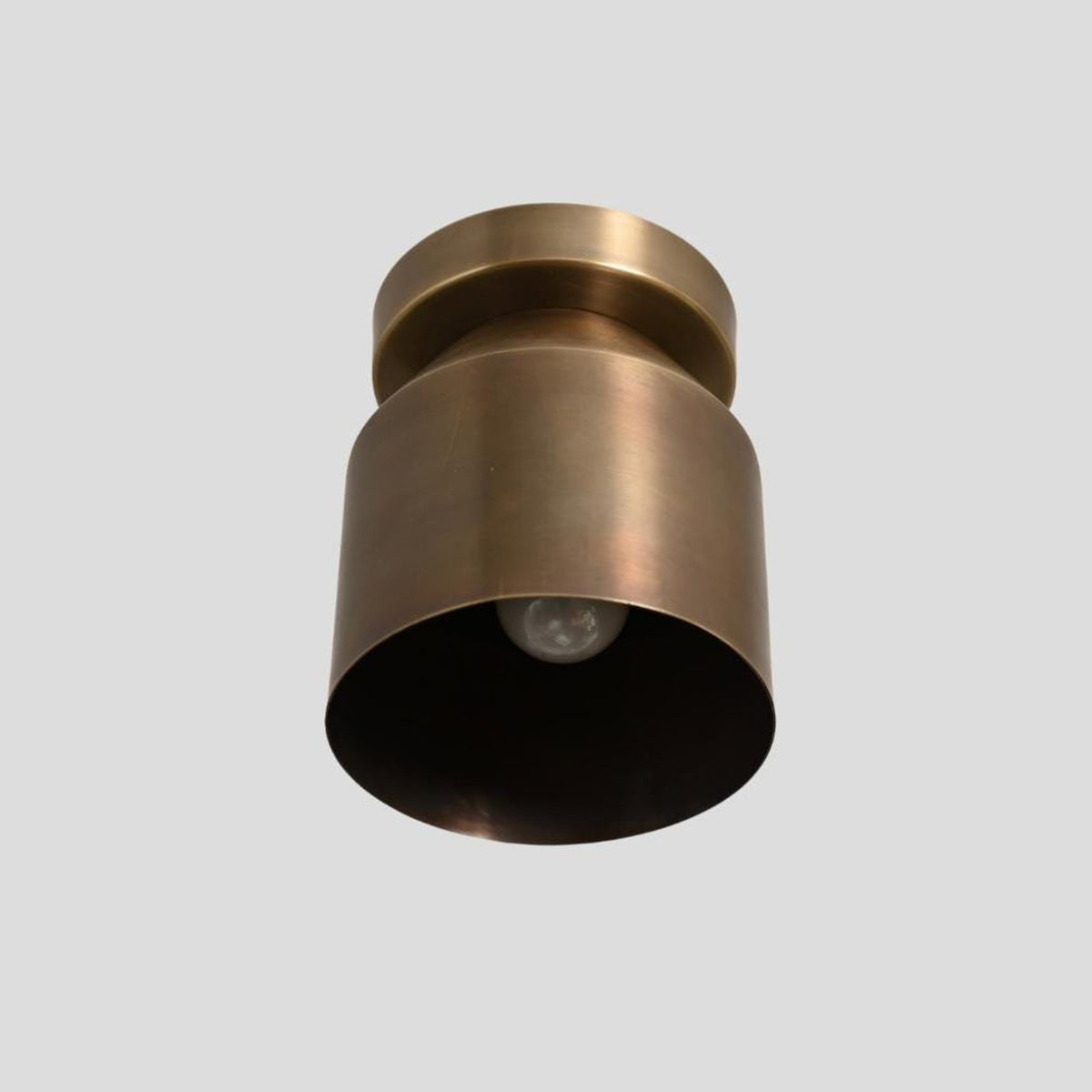 Bottom view of brass cylinder flush mount ceiling light with exposed bulb design
