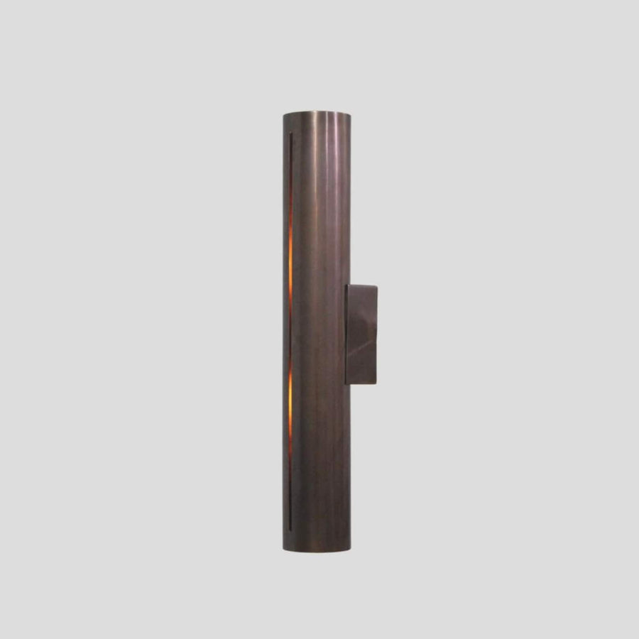 Handmade brass cylinder wall sconce light with warm glow, minimalist industrial design, crafted by Brass Leaf Studio.