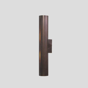 Handmade brass cylinder wall sconce light with warm glow, minimalist industrial design, crafted by Brass Leaf Studio.
