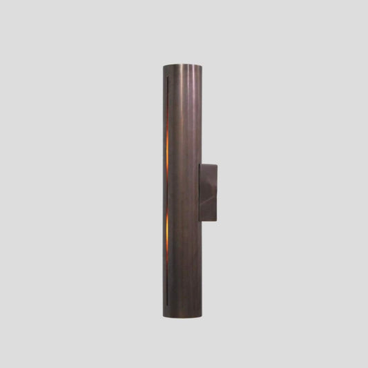 Handmade brass cylinder wall sconce light with warm glow, minimalist industrial design, crafted by Brass Leaf Studio.