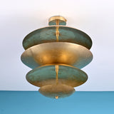 Low angle view of handcrafted brass disc ceiling light highlighting layered bowl shades and warm indirect illumination.