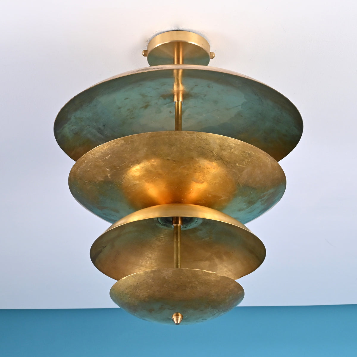 Low angle view of handcrafted brass disc ceiling light highlighting layered bowls and soft indirect illumination.