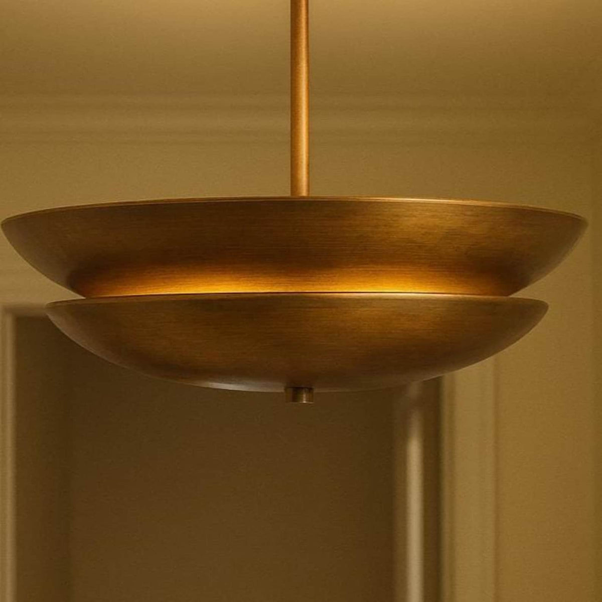 Close-up of brushed brass layered disc chandelier highlighting warm indirect lighting design