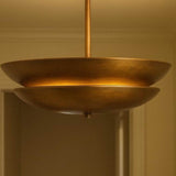 Close-up of brushed brass layered disc chandelier highlighting warm indirect lighting design