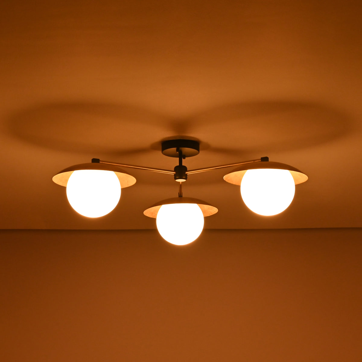 3 light brass disc flush mount ceiling light shown in a dark room with warm diffused illumination.
