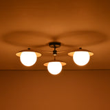 3 light brass disc flush mount ceiling light shown in a dark room with warm diffused illumination.
