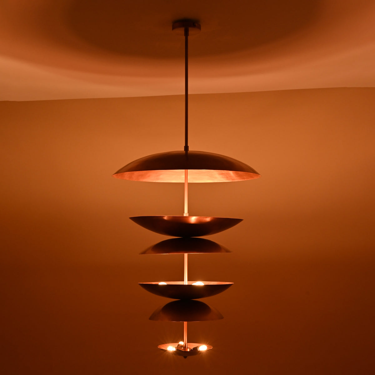 Nighttime ambiance shot of 9-light brass disc chandelier highlighting its layered dome design and soft glowing illumination