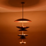 Nighttime ambiance shot of 9-light brass disc chandelier highlighting its layered dome design and soft glowing illumination