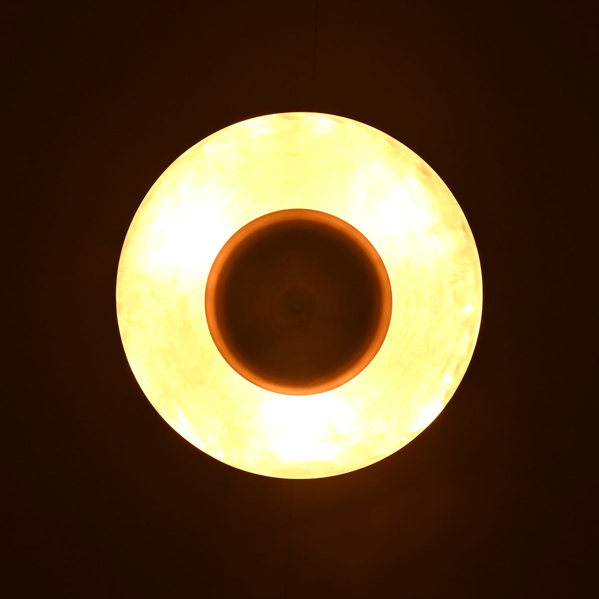 Top-down glowing view of brass pendant light emitting warm indirect illumination