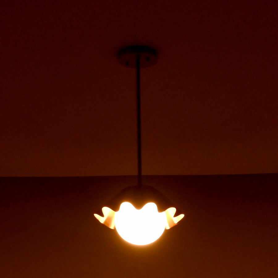 Minimalist brass fluted pendant light hanging straight with sculpted shade and glowing globe.