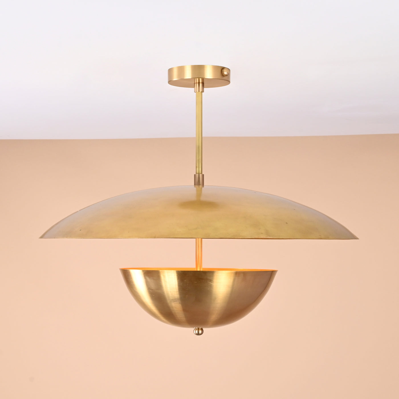 Handmade brass disc pendant light with dual dome design in brushed brass finish, shown against beige background