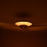 Warm ambient lighting from brass disc chandelier showing indirect uplight effect in a dim interior