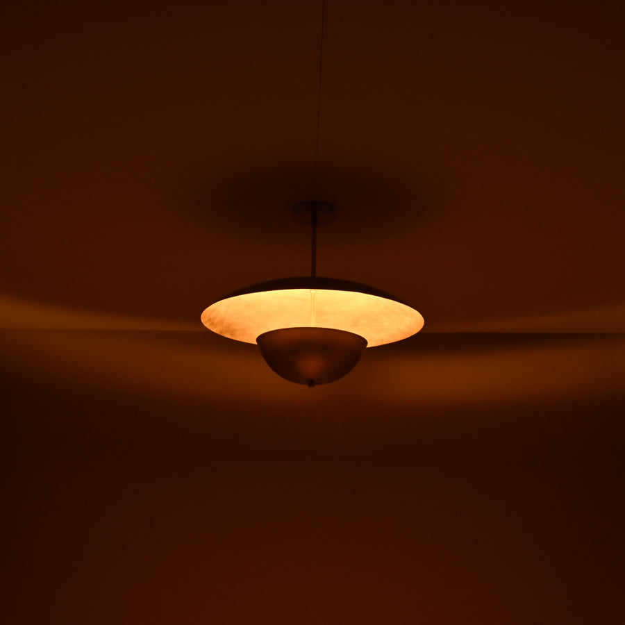 Handmade brass disc pendant light with dual dome design in brushed brass finish, shown against beige background