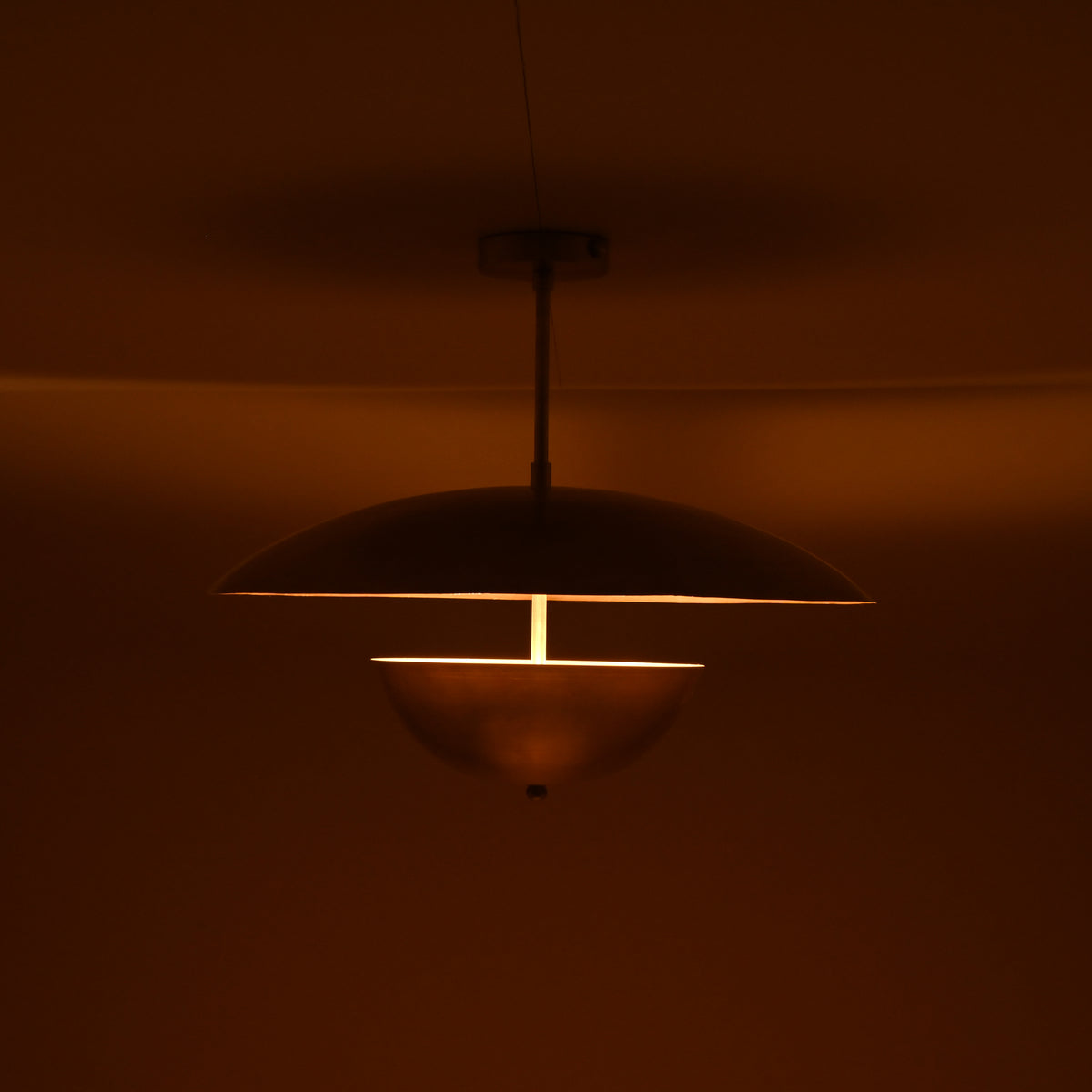 Night ambiance shot of brass dome pendant light showcasing warm atmospheric glow and minimalist silhouette