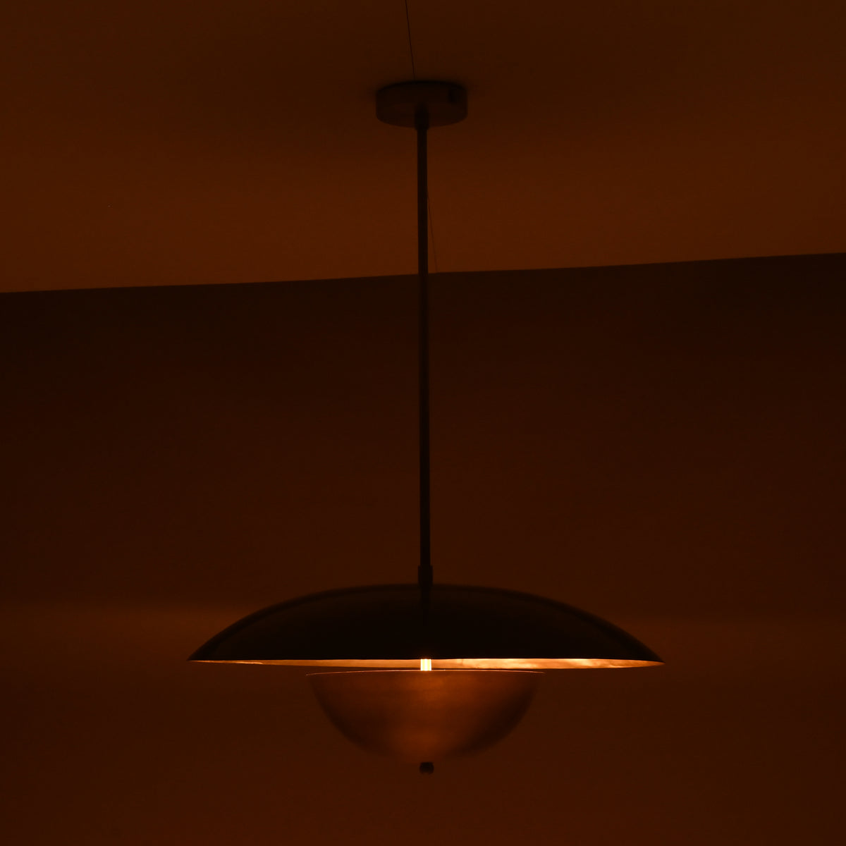 Evening ambiance shot of brass dome pendant with soft downward glow and golden ceiling illumination