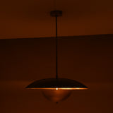 Evening ambiance shot of brass dome pendant with soft downward glow and golden ceiling illumination