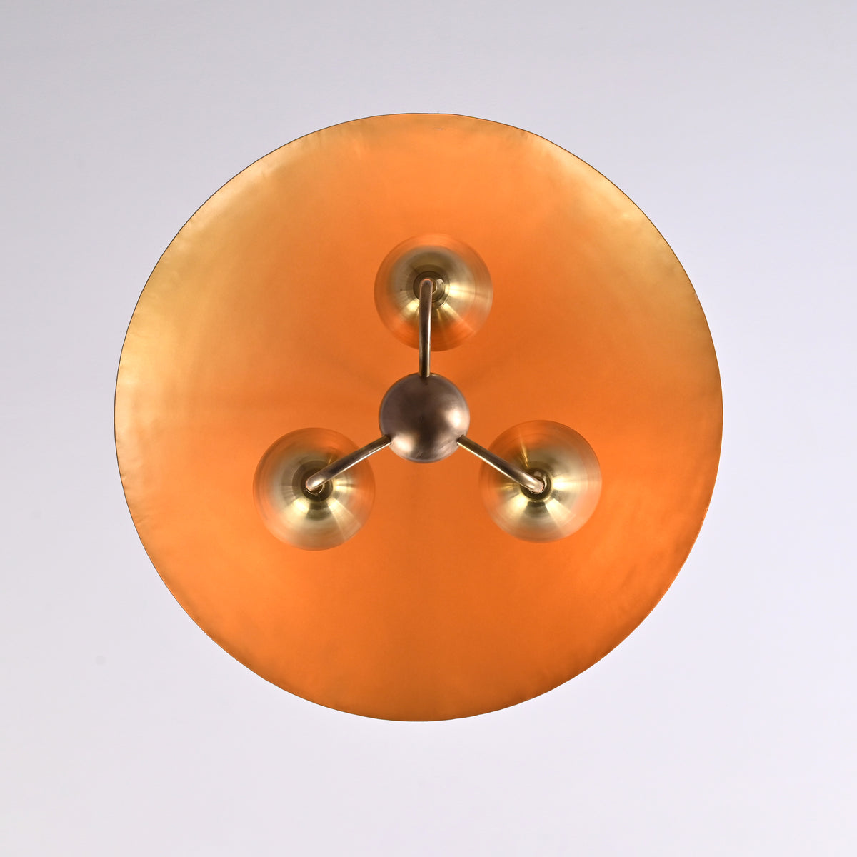 Bottom view of brass dome chandelier showcasing three-light configuration and round brass diffuser with mid-century elegance.