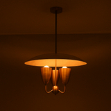 Studio shot of brass dome chandelier with warm indirect lighting, featuring dome shade and three brass cups in mid-century style.