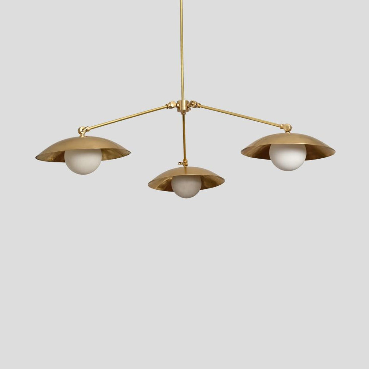 Modern brass chandelier featuring three frosted globe lights set in dome-shaped brass shades, handcrafted pendant for dining or living spaces.